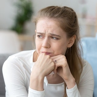 Ein Paar sitzt nebeneinander auf der Couch, beide sehen unglücklich aus mit der Beziehung