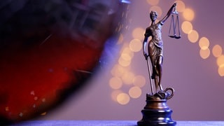 Eine Bronzestatue der Justitia steht auf einem Tisch und symbolisiert das Verkehrsrecht